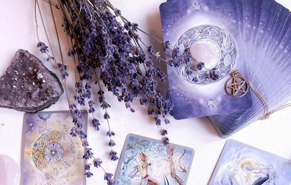 deck of tarot cards beside dried flowers and crystals on a white surface